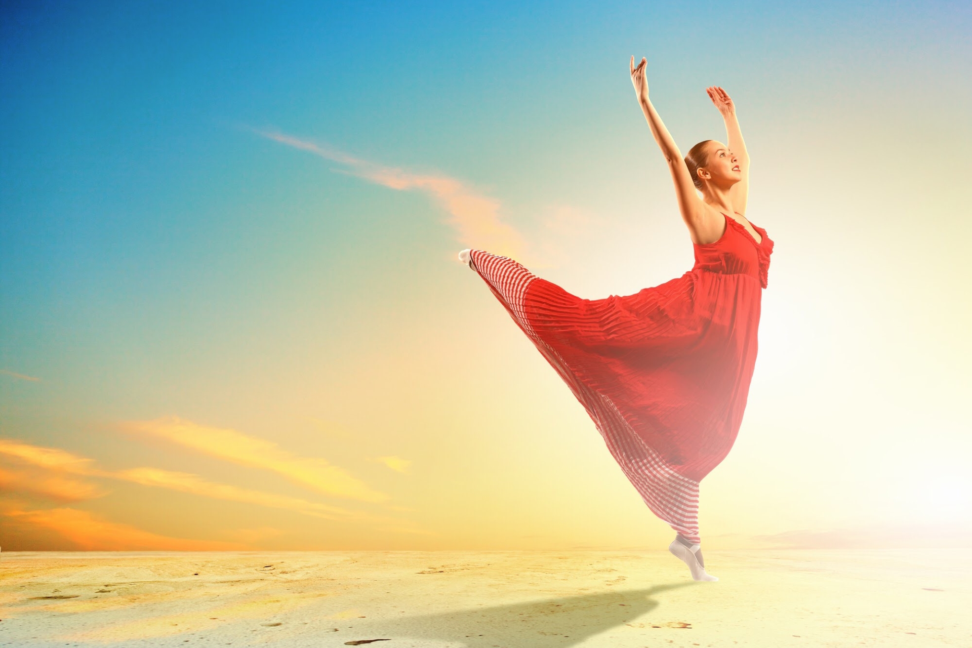 Kvinna, dansandes i en röd klänning, har armarna sträckta uppåt.